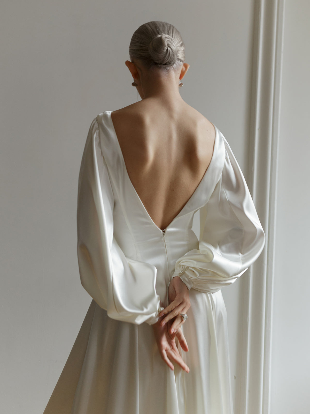 Back view of the satin wedding dress showing the open back and bishop sleeves.