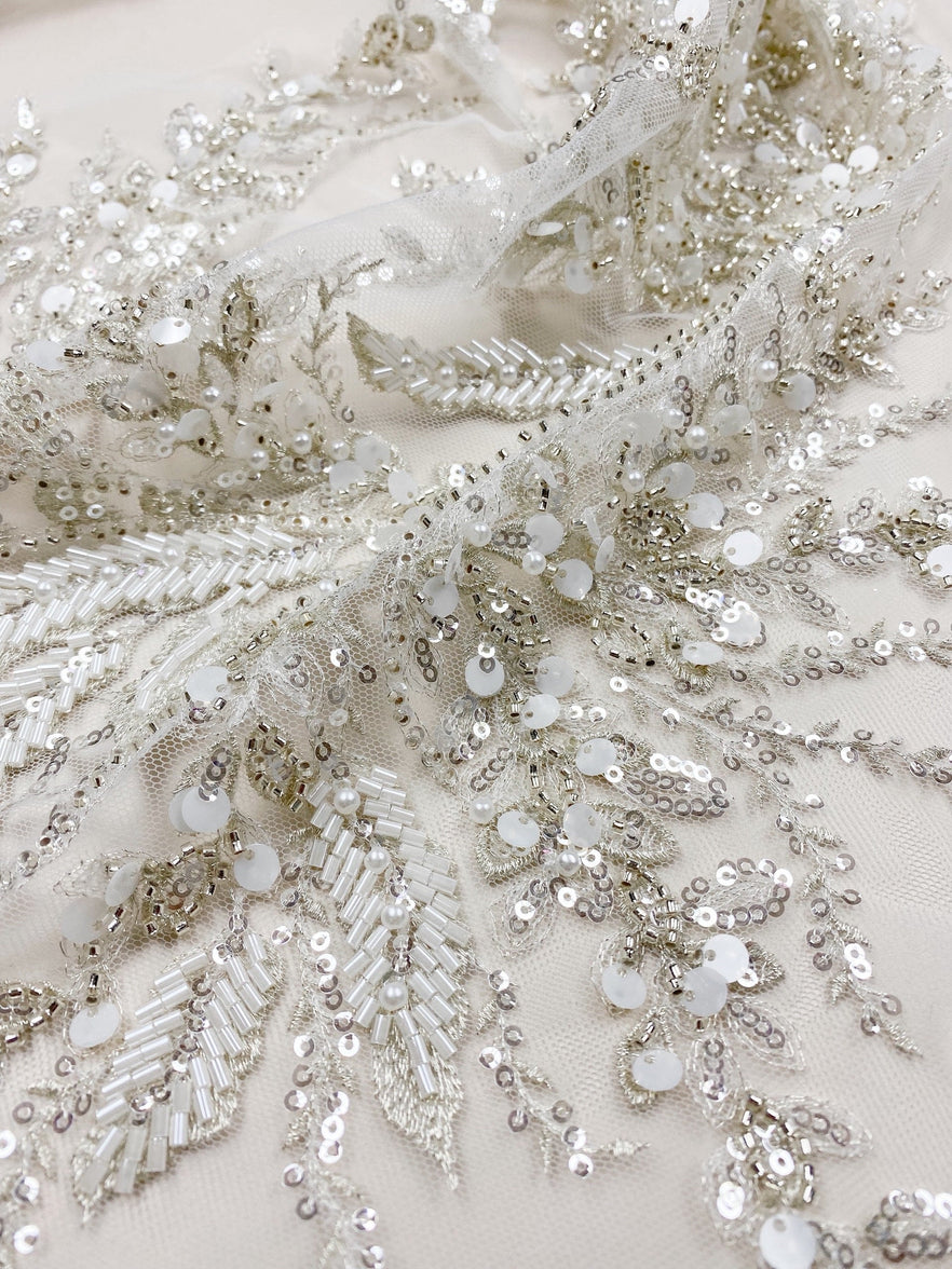 Silver beaded leaf-pattern embroidery hand-applied on sheer mesh — close-up of individually placed beadwork