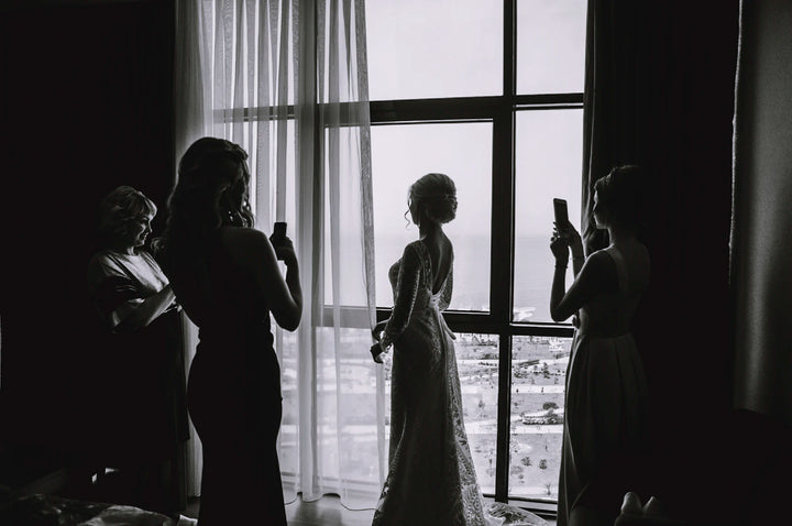 Silhouette of a bride in a wedding gown against bright light, full dress shape visible from head to floor
