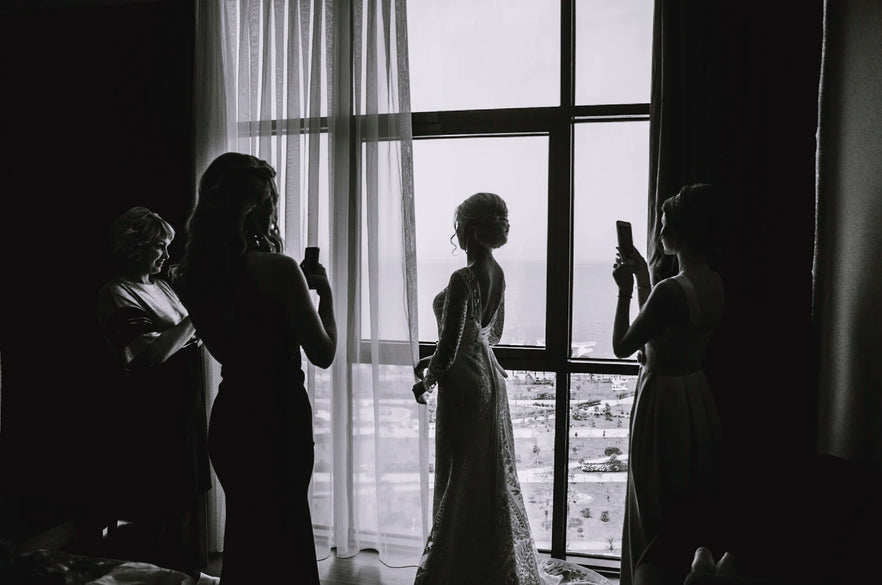 Silhouette of a bride in a wedding gown against bright light, full dress shape visible from head to floor