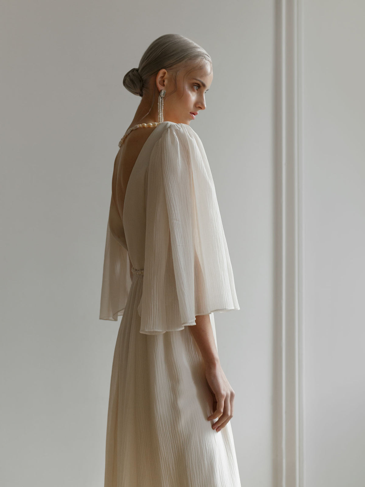 Full-length view of the ivory crash-chiffon wedding dress showing the V-neckline and skirt drape.