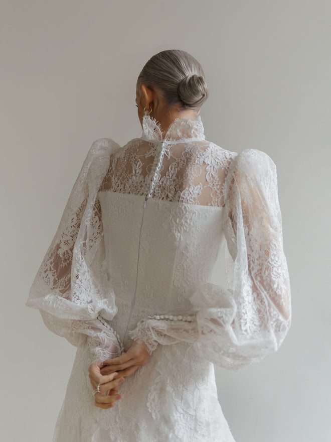 Back view of the high-neck lace wedding dress showing a row of covered buttons.